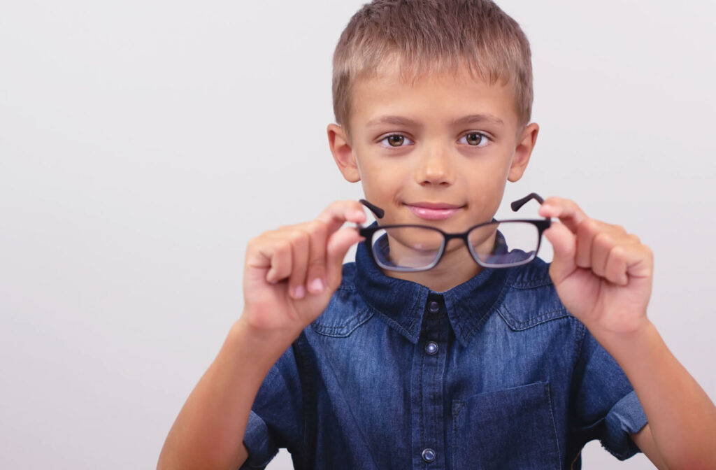 A young boy holding correcting glasses formyopia control