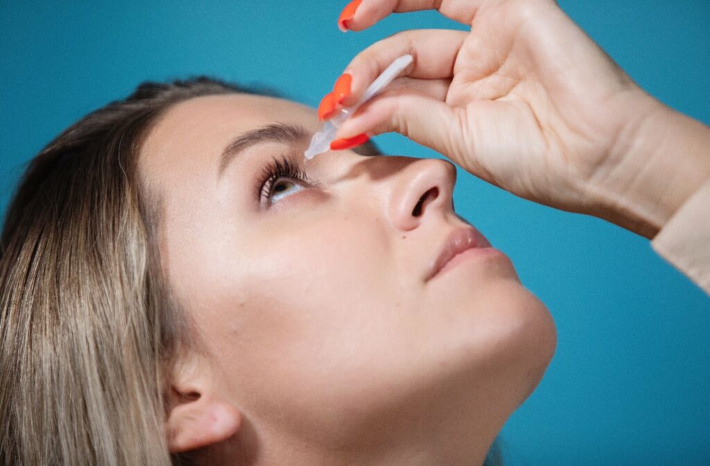 A close-up of a woman applying atropine eyedrops on her right eye.