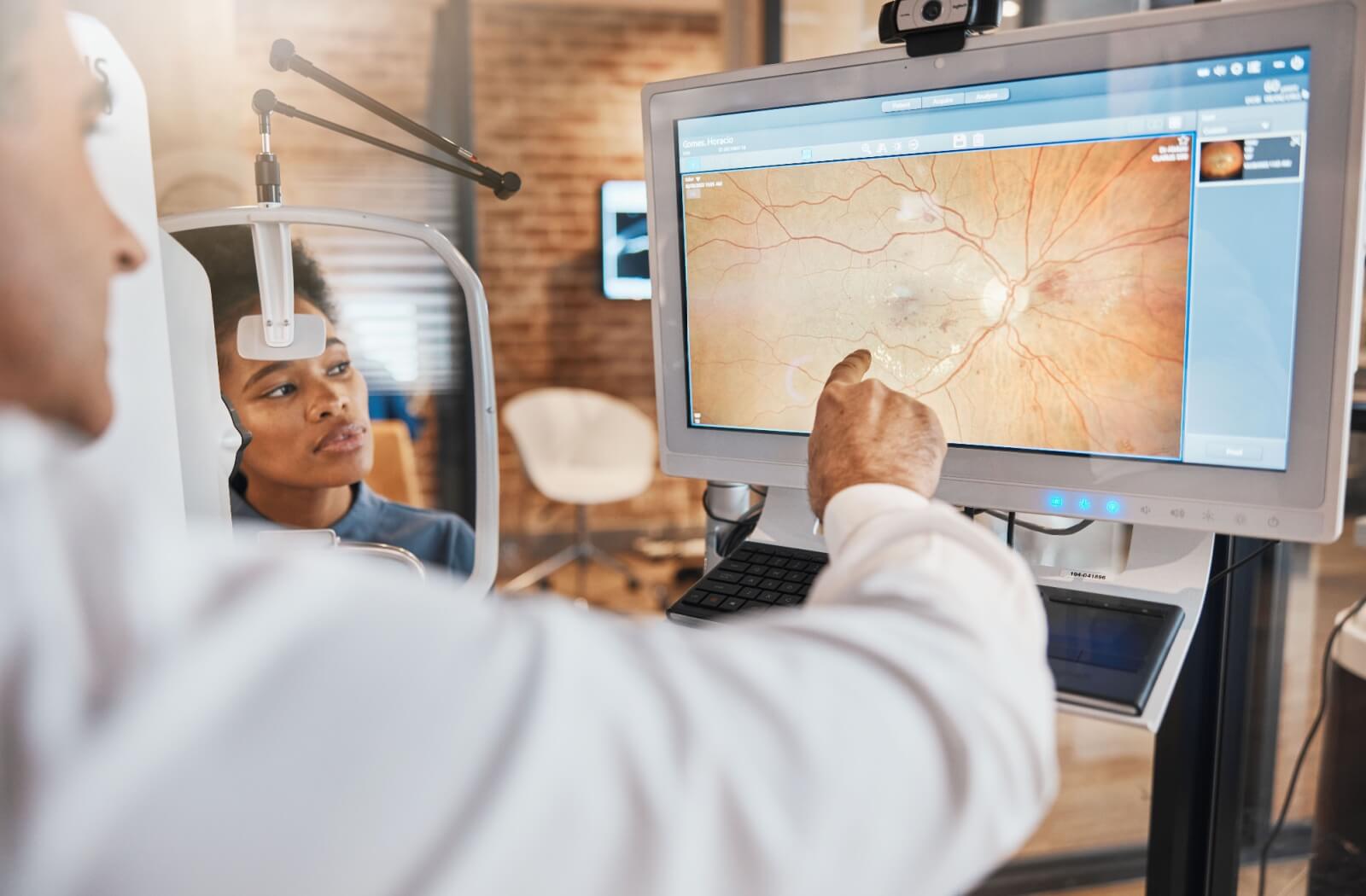 An optometrist explains the details of their patient's retinal images during their routine eye exam.