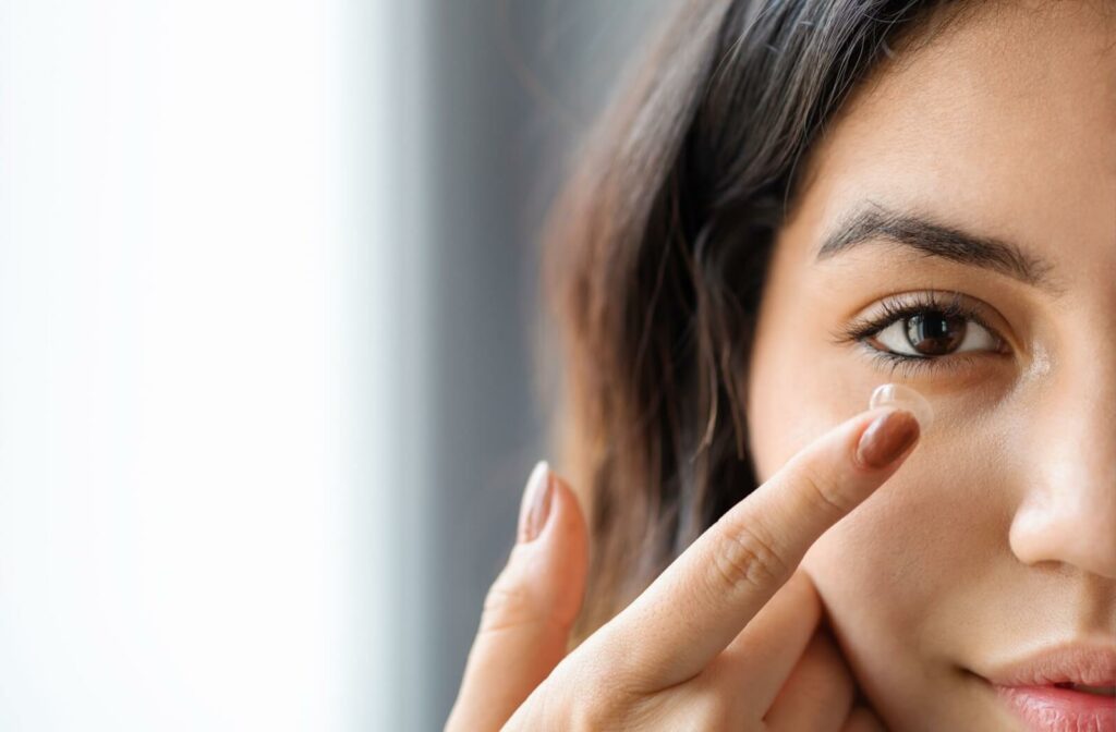 A closeup showing a young woman inserting her contact lens.