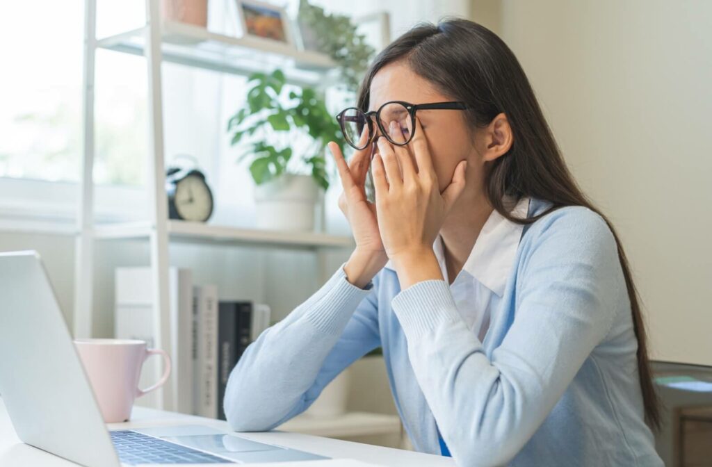 A young woman rubs her eyes from irritation caused by dry eyes.