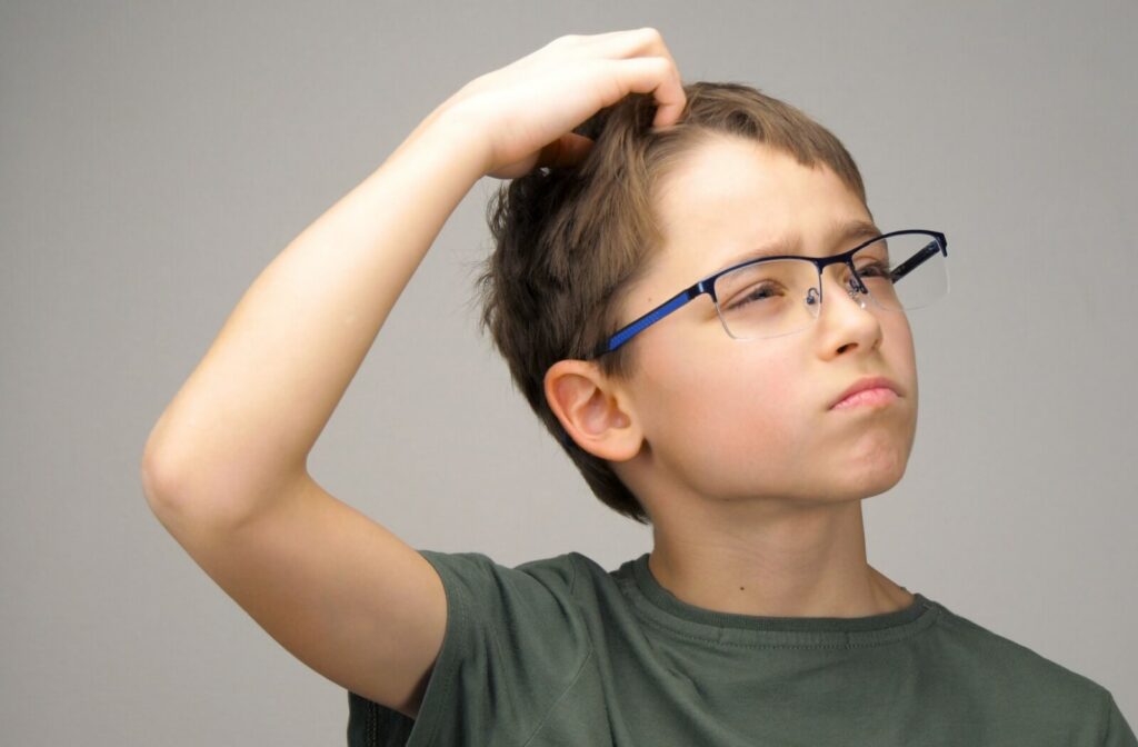 A young child wearing glasses scratching his head in wonder