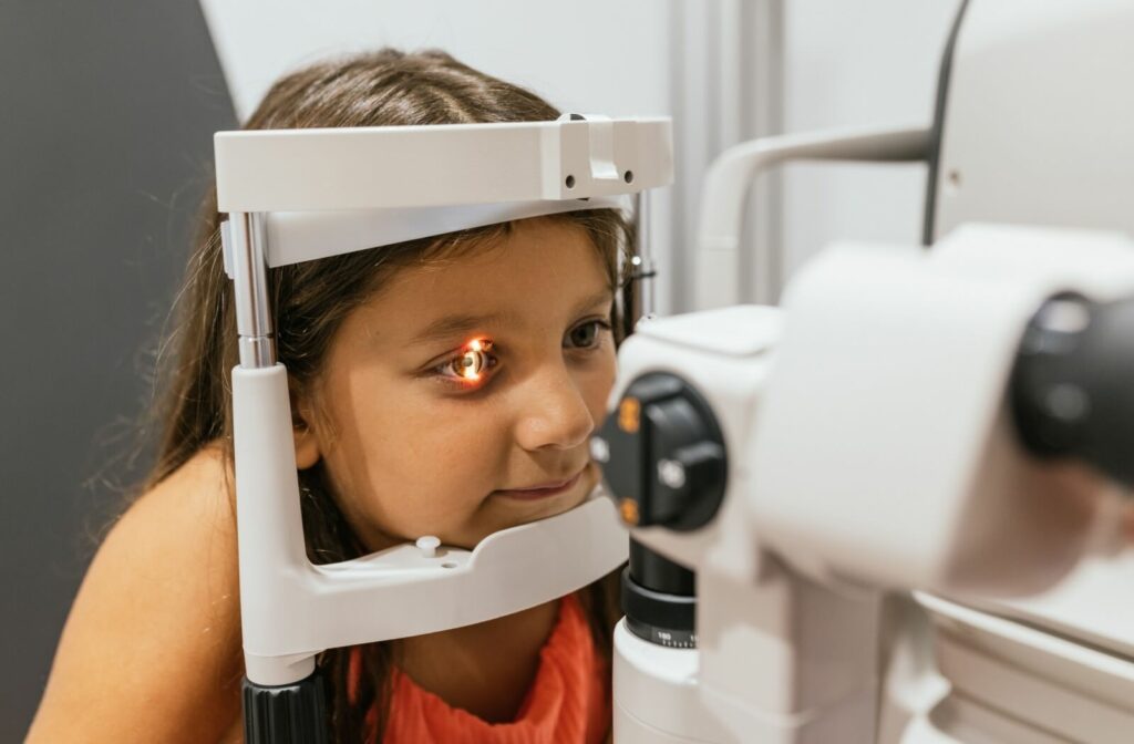 A young child undergoing an eye exam with a slit lamp, which shines a bright light to examine the health and structure of the eye