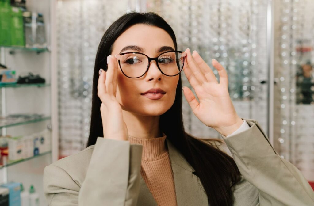 An adult tries on new eyeglasses in their optometrist's showroom.