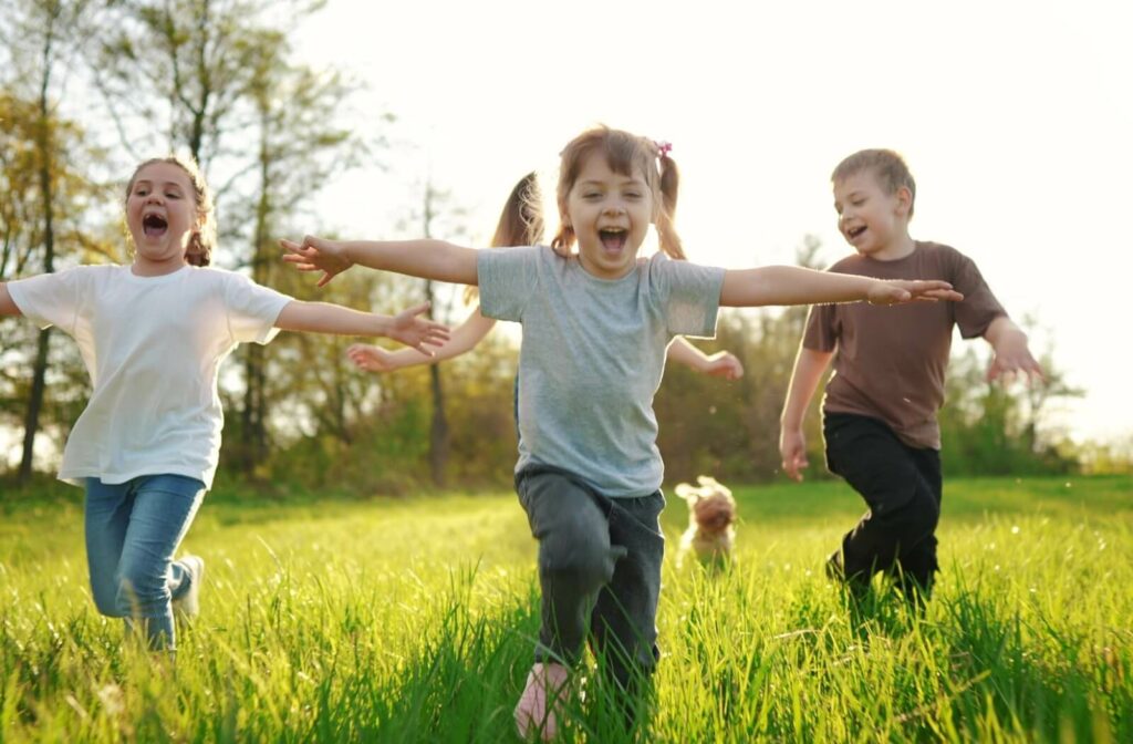 A group of children running in a field. None of them are wearing glasses.