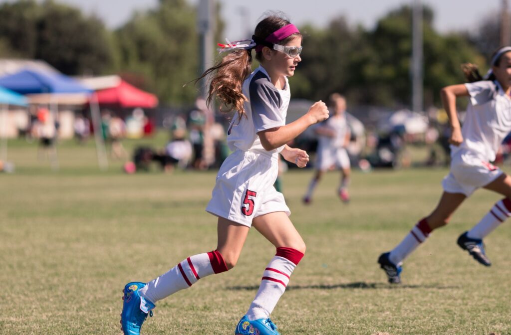 A child wearing glasses while playing soccer