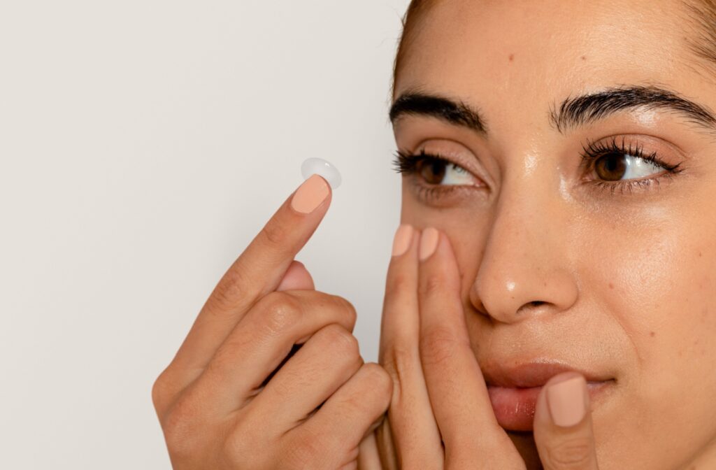 A close-up photo of someone inserting a contact lens into their eye.