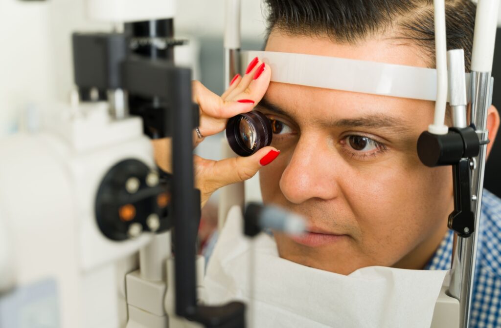 An adult has their eyes examined by an optometrist with a magnification tool.