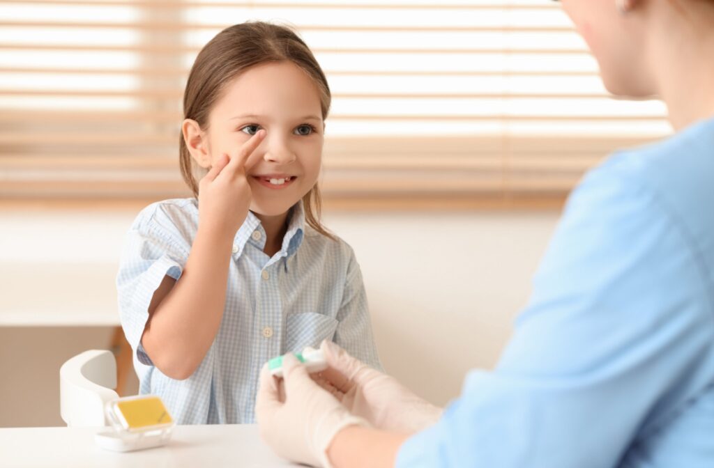 A child being supervised by an adult as they put in their own contact lenses